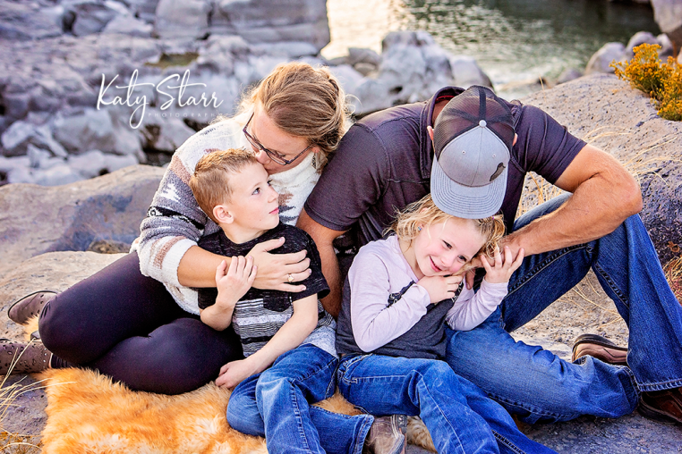mom, dad, son and daughter cuddling for family pictures in the snake river canyon